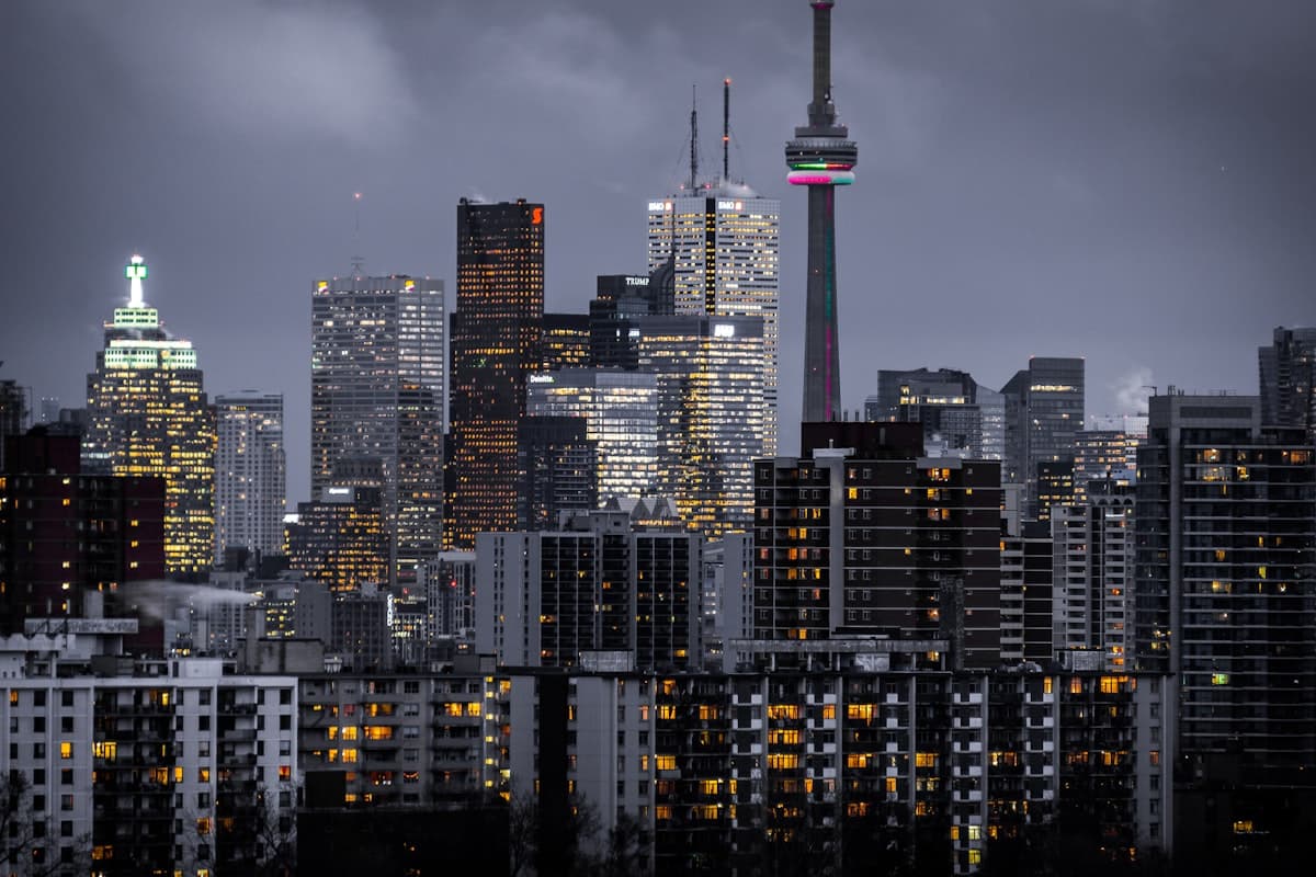 The Toronto skyline at nightfall, the CN Tower rising over lit office and apartment windows